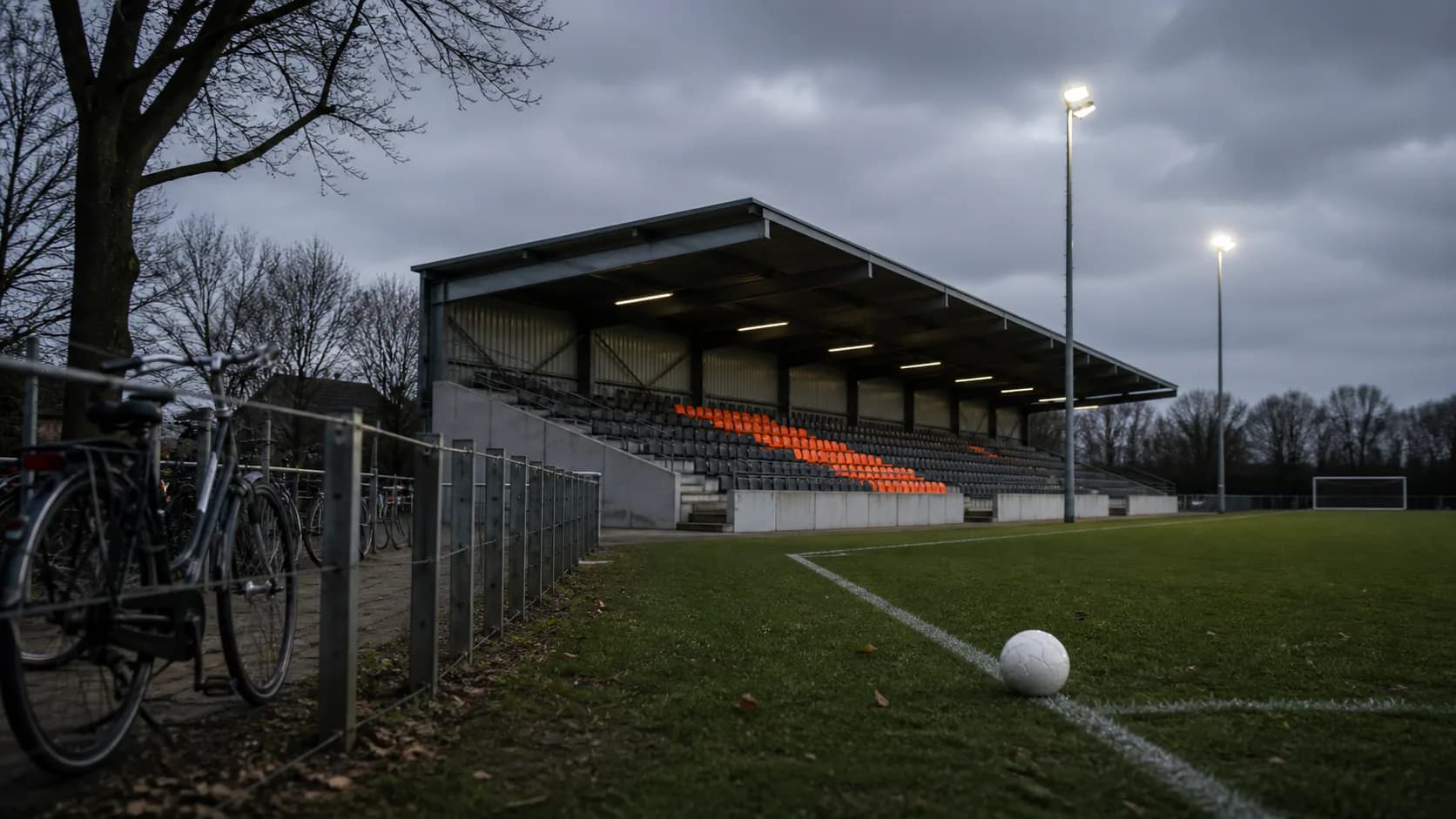Nederlands voetbalveld met fietsen en een lege tribune