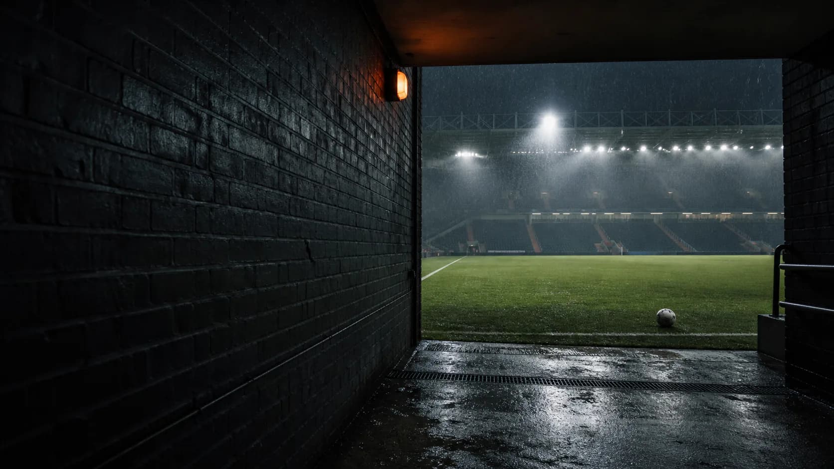 Regenachtig voetbalstadion gezien vanuit een donkere spelerstunnel